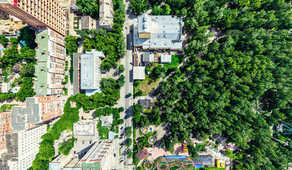 Fototapeta premium Aerial city view with crossroads and roads, houses, buildings, parks and parking lots, bridges. Helicopter drone shot. Wide Panoramic image.