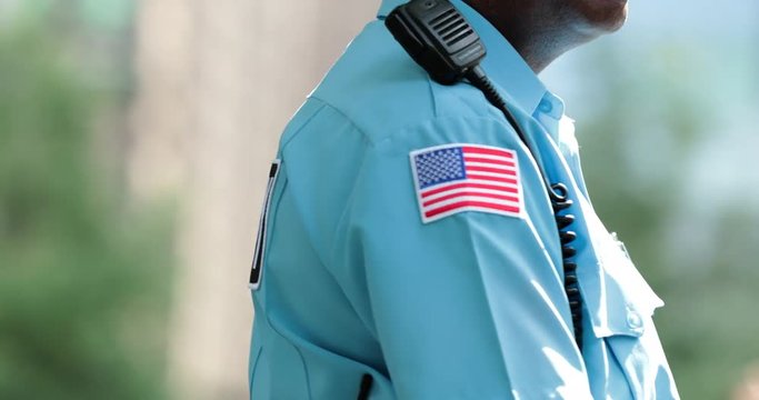 American flag attached to security uniform walking slowly overlooking public protection