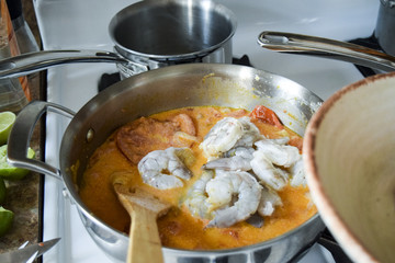 Stirring raw shrimp into Brazilian stew