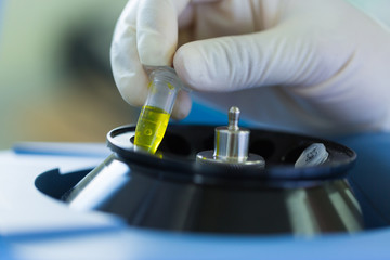 Scientist putting test tube into centrifuge	