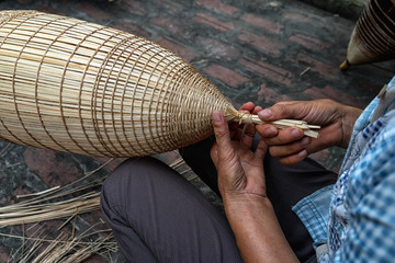 Closeup Old Vietnamese female craftsman hands making the traditional bamboo fish trap or weave at the old traditional house in Thu sy trade village, Hung Yen, Vietnam, traditional artist concept