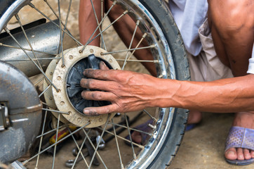 mechanic changing motorcycle tire by traditional method