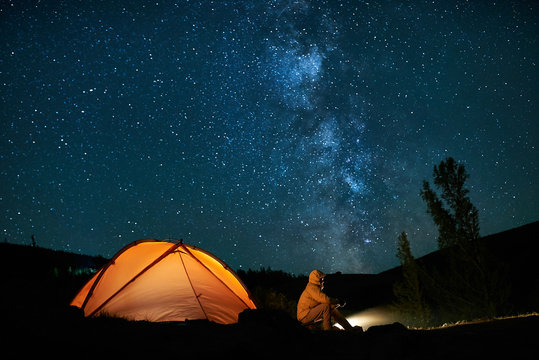 Man tourist near his camp tent at night.