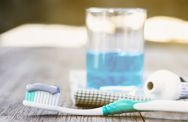 Toothbrush with toothpaste and mouthwash on wooden table.