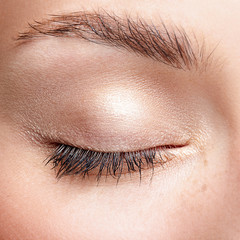Closeup macro shot of closed human female eye with natural day face beauty make up