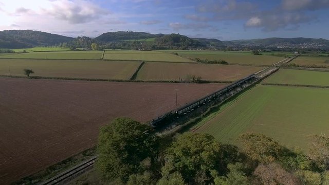 An old English steam train powering through the countryside.