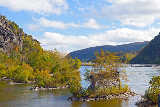 Shenandoah River with old bridge remains in Harpers Ferry, West Virginia, USA. Blue Ridge Mountain in Harpers Ferry National Historical Park in autumn.