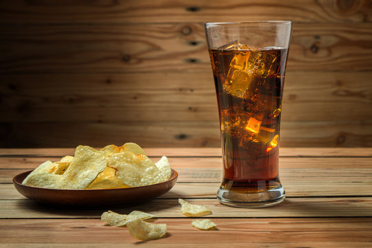 Potato chips with cola on a wooden background