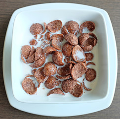 Breakfast cereal with milk, Cornflakes in white bowl.