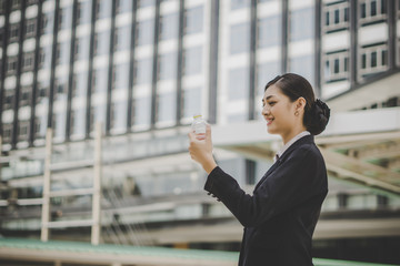 Fototapeta premium Business woman take a rest drinking water in front of business center.