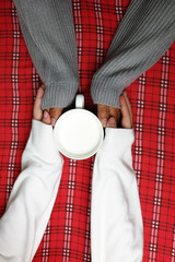 Hand holding on winter with warm drink on red table cloth