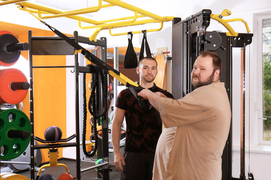 Overweight Man With Trainer In Gym