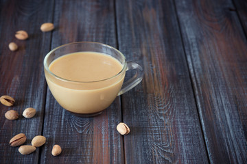 Coffee with milk and pistachios on the table, copy space
