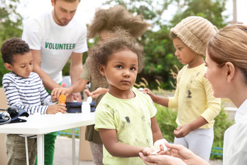 Volunteers giving vitamin tablets to poor African children outdoors