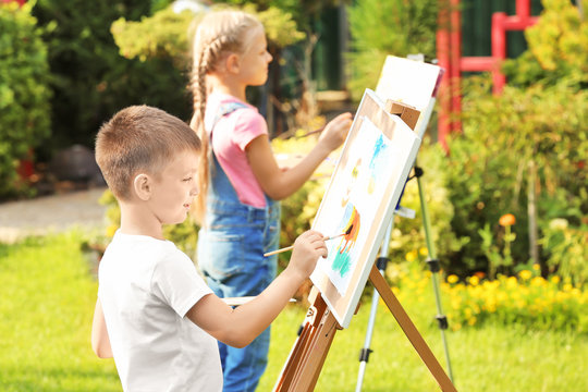 Cute little children painting picture, outdoors