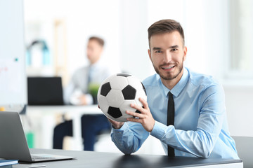 Young handsome man with soccer ball in office © Africa Studio