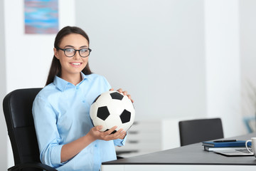Young beautiful woman with soccer ball in office