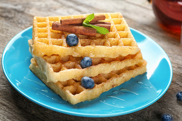 Plate with delicious cinnamon waffles on table