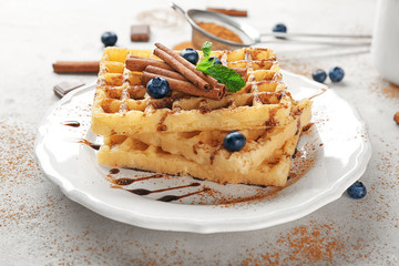 Plate with delicious cinnamon waffles on table