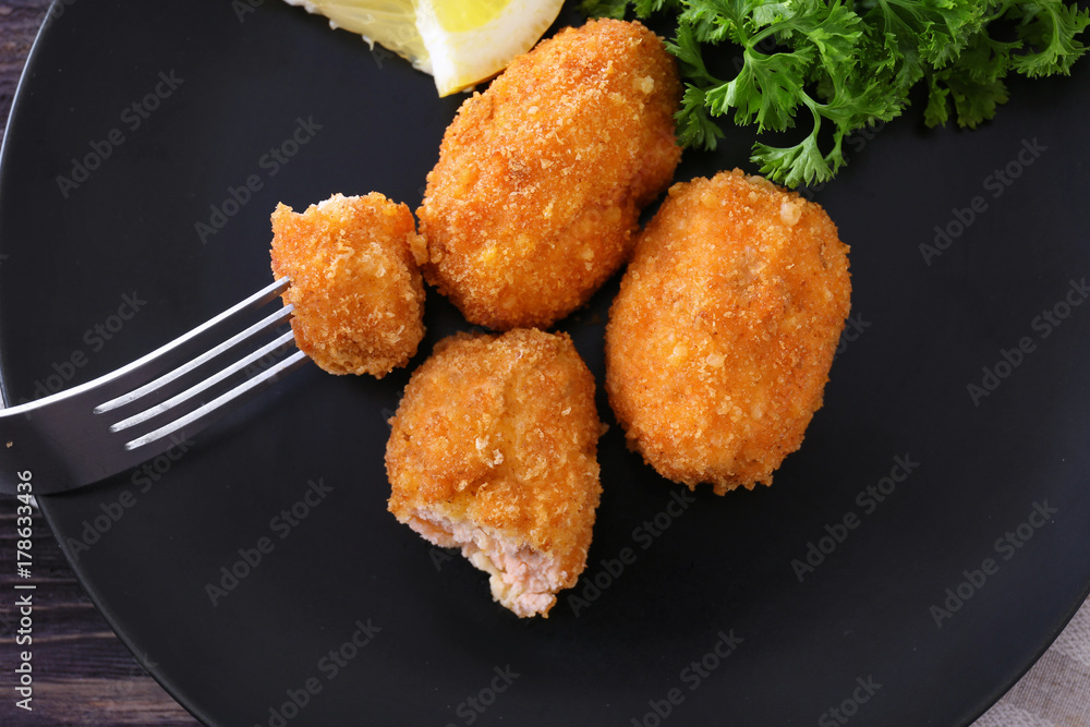 Sticker Fork with piece of salmon croquette on plate, closeup