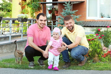 Male gay couple with adopted baby girl, outdoors
