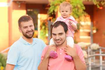 Male gay couple with adopted baby girl, outdoors