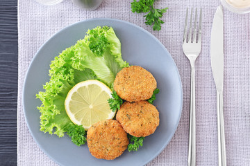Plate with delicious salmon patties on table