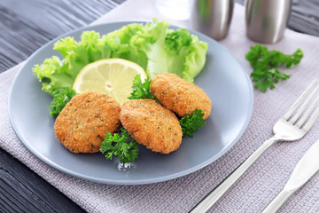 Plate with delicious salmon patties on table