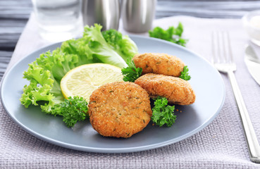 Plate with delicious salmon patties on table