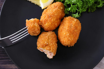 Fork with piece of salmon croquette on plate, closeup