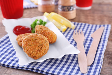 Paper plate with delicious salmon patties on table