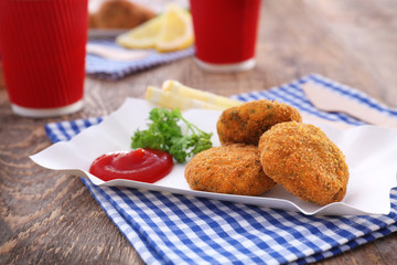 Paper plate with delicious salmon patties on table