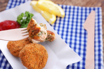 Fork with piece of delicious salmon patty over plate, closeup