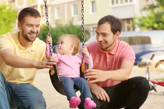 Male gay couple with adopted baby girl, outdoors