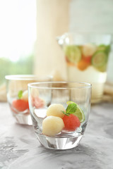 Glass with melon ball drink on table