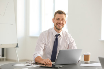 Young male professional working at table in office