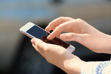 Woman using cell phone to call taxi on street, closeup