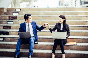 Young business couple sitting on staircase working some before go work on  laptop.