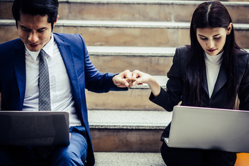 Young business couple sitting on staircase working some before go work on  laptop.