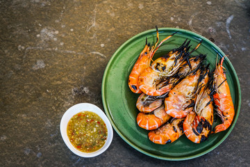 On top grilled prawn, giant freshwater prawn shrimp on green ceramic dish with seafood sauce dipping