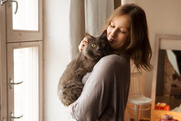 Young woman playing with cat in home.
