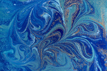 Marbled blue abstract background with golden sequins. Liquid marble ink pattern.