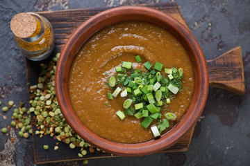 Above view of cream-soup with peas and curry topped with fresh greens, horizontal shot