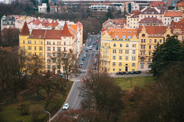 View from a high point. A beautiful view from above on the streets, roads and roofs of houses in Prague. Traditional ancient urban architecture. The road, the car is parked, ordinary life.