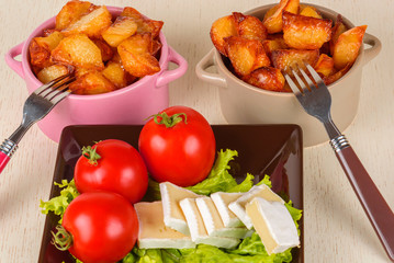 Breakfast from cheese, tomatoes, potatoes and all-over salad on a wooden table closeup.