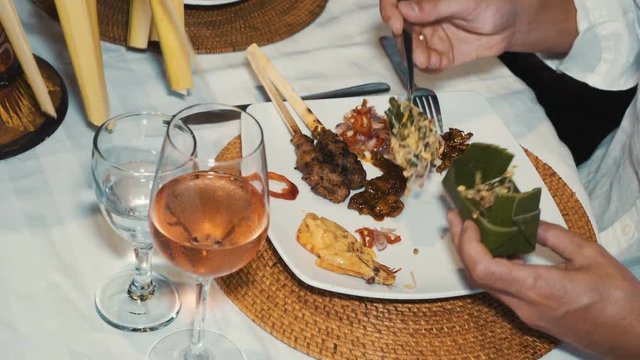 Close up of man hands adding some balinese food to his plate at dinner