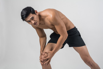 Obraz premium Young sport man with strong athletic legs holding knee with his hands in pain after suffering ligament injury isolated on white.