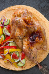 Oven baked half chicken served on tortilla bread with fresh vegetables, close-up, elevated view