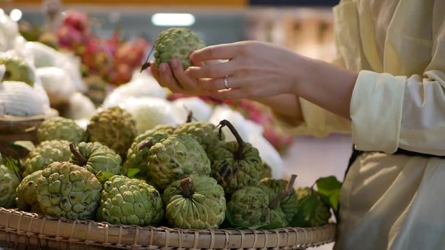 Womans hands choosing the custard apple or sugar apple in the supermarket