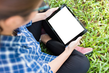 Mockup image of an asian woman sitting and holding black tablet with blank white screen